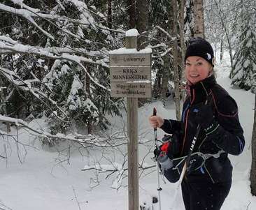 A woman standing next to a sign in the snow.