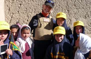 A woman in a uniform posing with a group of children.